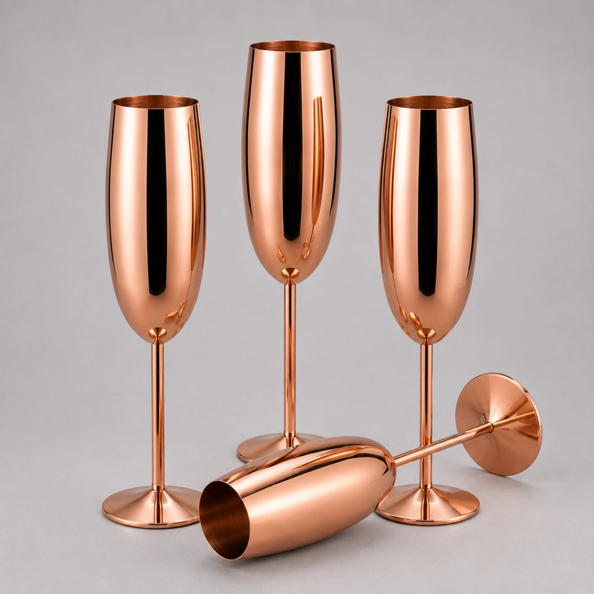 Three copper-colored champagne flutes with matching stemware pieces arranged on a light gray studio background.