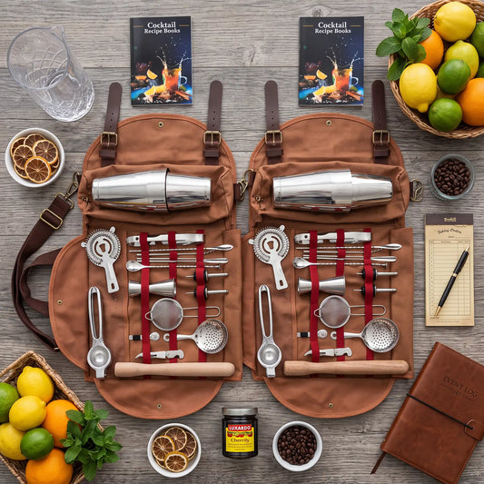 A bar tool set arranged in an open brown canvas roll-up pouch on a rustic wood surface, with cocktail recipe books, lemons, limes, oranges, coffee beans, a glass, and a brown notebook around it. The set includes metal shaker parts, strainers, jiggers, muddler, spoon, and other bartending tools.