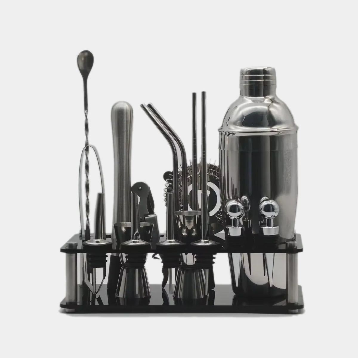 A 16-piece stainless steel cocktail bar tool set with a black acrylic organizer tray, including a shaker, jigger, strainers, and bar spoons, shown on a light gray background.