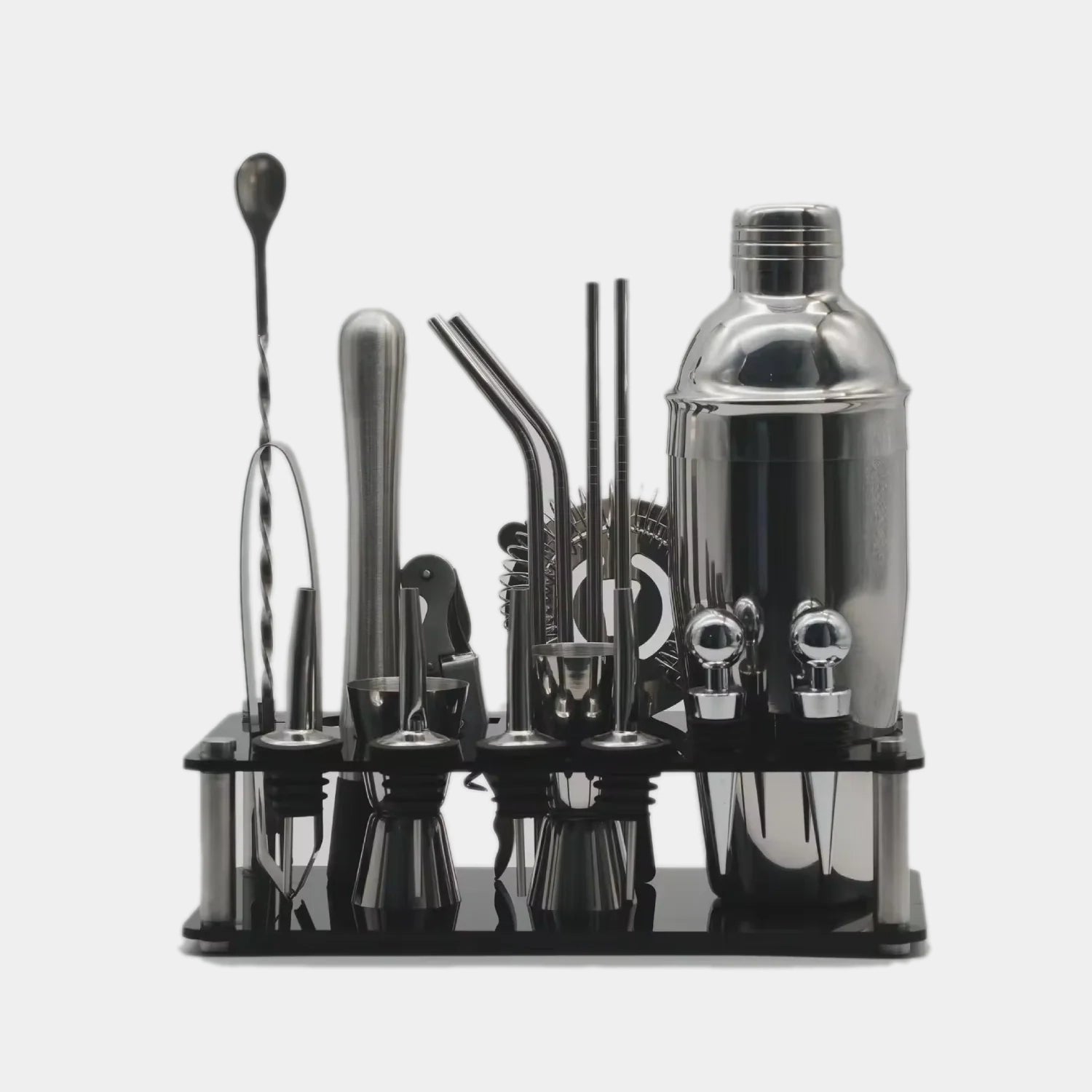 A 16-piece stainless steel cocktail bar tool set with a black acrylic organizer tray, including a shaker, jigger, strainers, and bar spoons, shown on a light gray background.