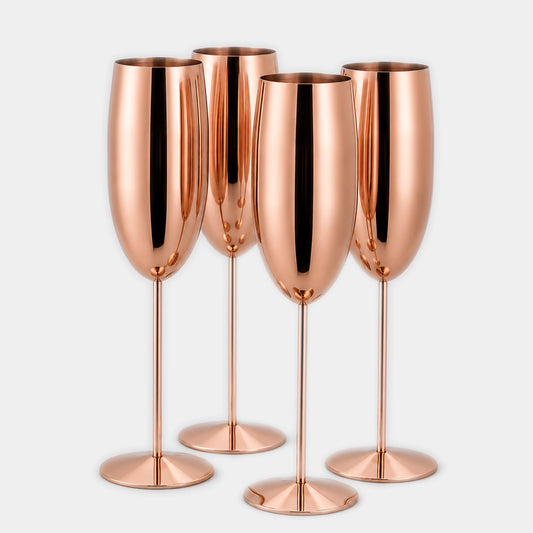 Four metallic rose gold champagne flutes with a polished, reflective finish, arranged in a group against a light gray background.