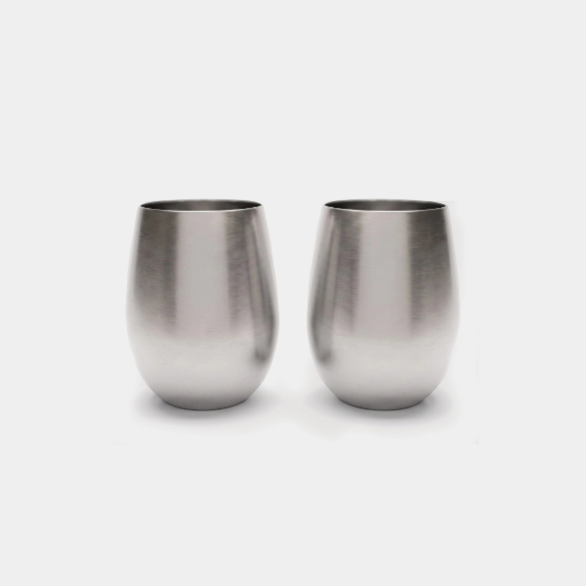 Two brushed stainless steel stemless wine glasses on a light gray background.